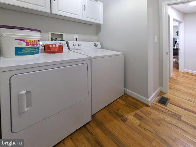 laundry room with hardwood / wood-style floors, cabinets, and independent washer and dryer