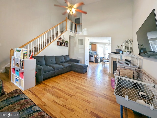 living room featuring hardwood / wood-style floors, a towering ceiling, and ceiling fan