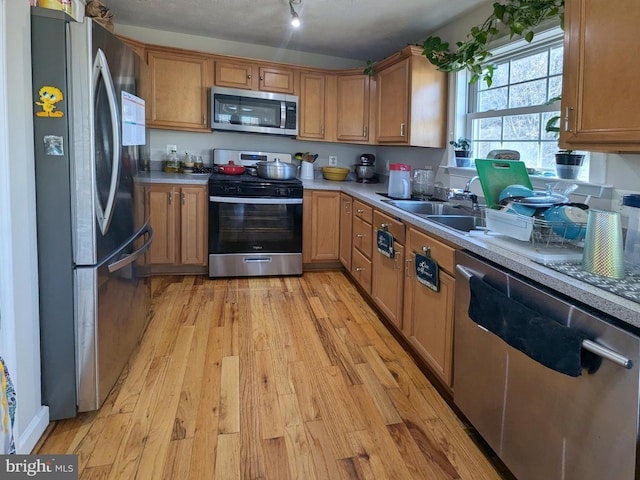 kitchen featuring sink, light wood-type flooring, a textured ceiling, and appliances with stainless steel finishes