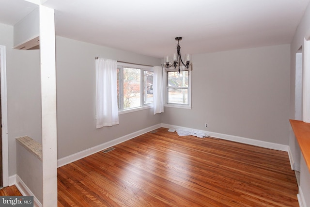 unfurnished dining area with hardwood / wood-style flooring and an inviting chandelier