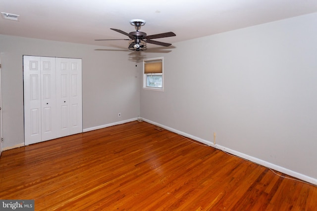 unfurnished bedroom with ceiling fan, wood-type flooring, and a closet