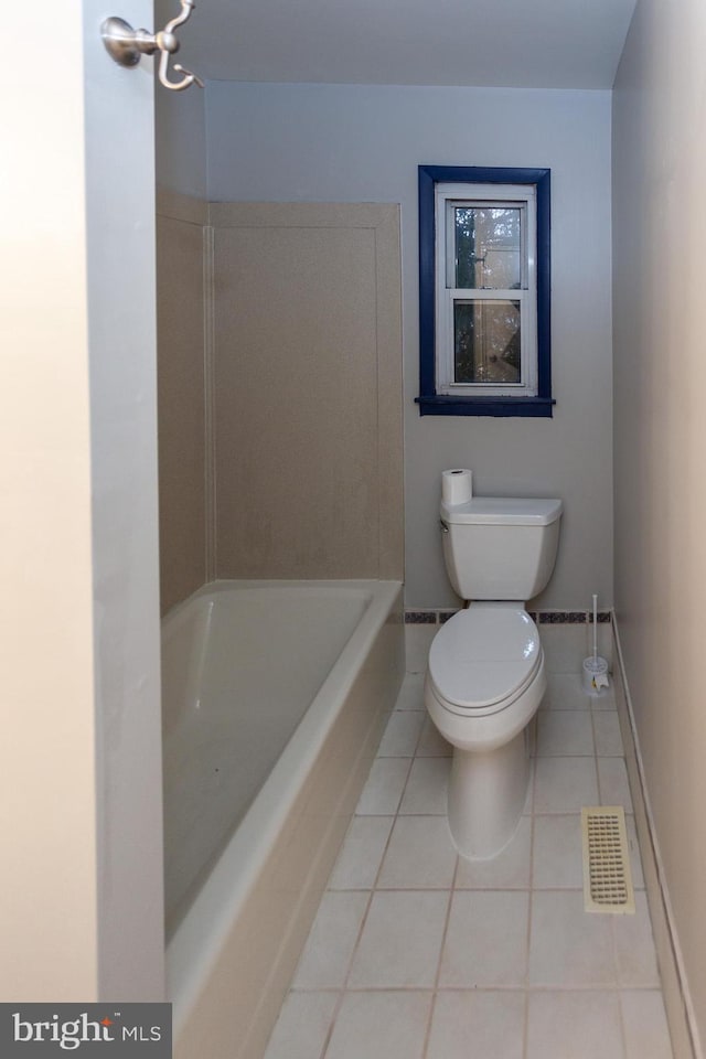 bathroom with tile patterned flooring, a bathtub, and toilet