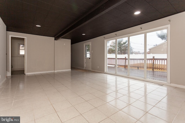 empty room with beamed ceiling and light tile patterned floors