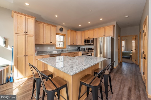 kitchen with dark wood-type flooring, a kitchen island, appliances with stainless steel finishes, and a breakfast bar