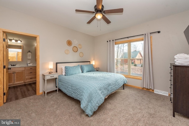 bedroom featuring light colored carpet, ceiling fan, and ensuite bathroom