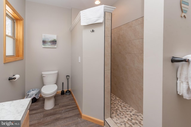 bathroom featuring tiled shower, hardwood / wood-style flooring, and toilet