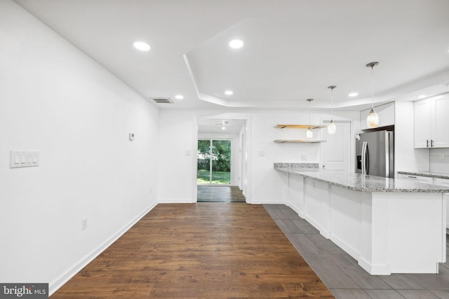 kitchen with white cabinetry, dark hardwood / wood-style flooring, pendant lighting, stainless steel refrigerator with ice dispenser, and kitchen peninsula