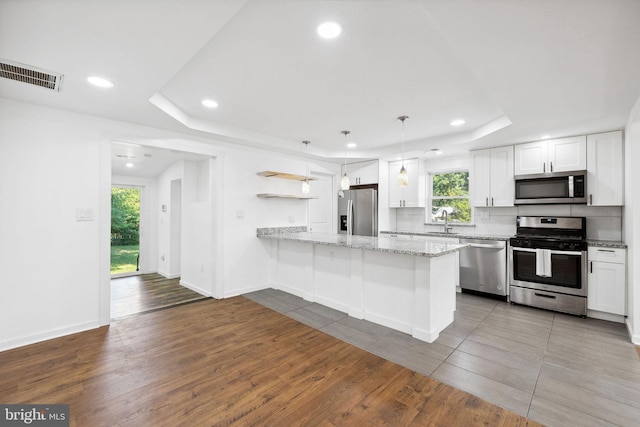 kitchen featuring white cabinetry, a wealth of natural light, appliances with stainless steel finishes, and pendant lighting