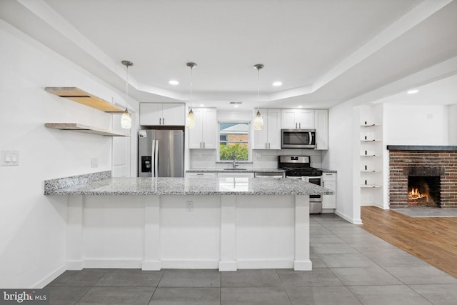 kitchen with white cabinets, kitchen peninsula, decorative light fixtures, and appliances with stainless steel finishes