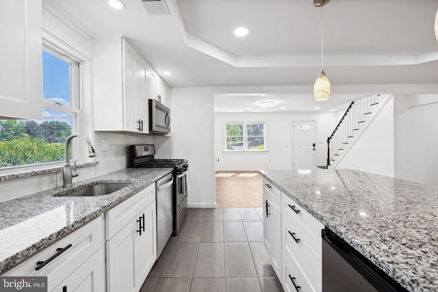 kitchen featuring white cabinets, appliances with stainless steel finishes, hanging light fixtures, and light stone countertops