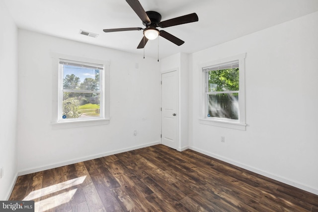 empty room featuring ceiling fan, dark hardwood / wood-style floors, and a healthy amount of sunlight