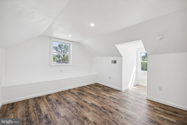 bonus room featuring dark wood-type flooring, vaulted ceiling, and a healthy amount of sunlight