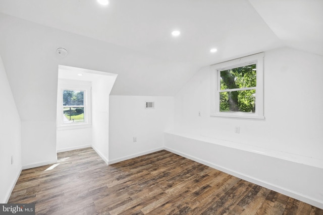 additional living space featuring vaulted ceiling, dark hardwood / wood-style floors, and plenty of natural light