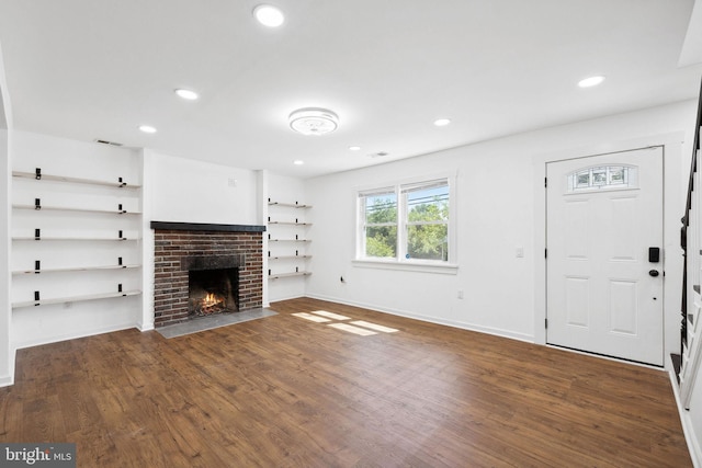 unfurnished living room featuring dark hardwood / wood-style flooring and a brick fireplace