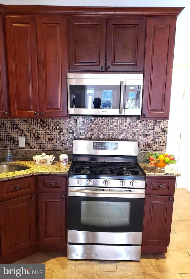 kitchen featuring light stone countertops, stainless steel appliances, tasteful backsplash, and sink