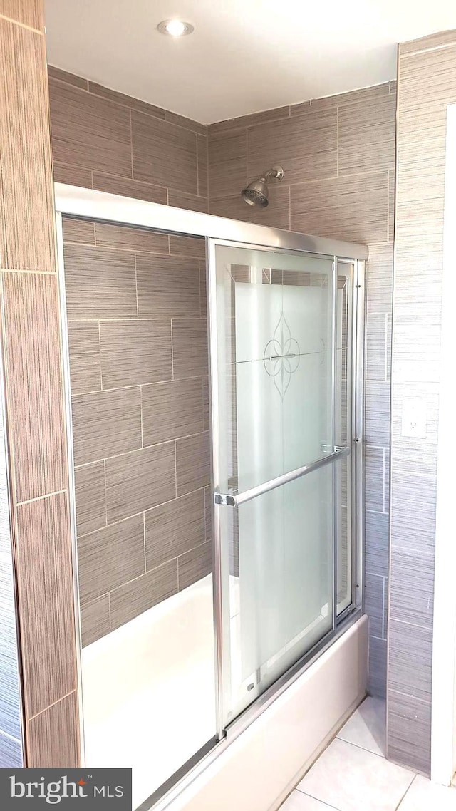 bathroom with shower / bath combination with glass door, tile patterned floors, and tile walls