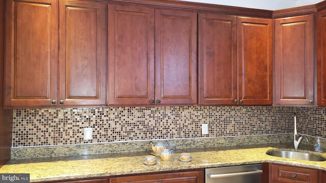 kitchen featuring dishwasher, tasteful backsplash, light stone countertops, and sink