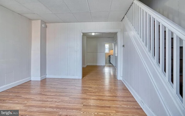 unfurnished room with light wood-type flooring and wooden walls