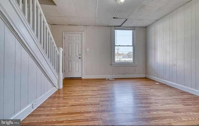 entryway with light hardwood / wood-style floors and wood walls