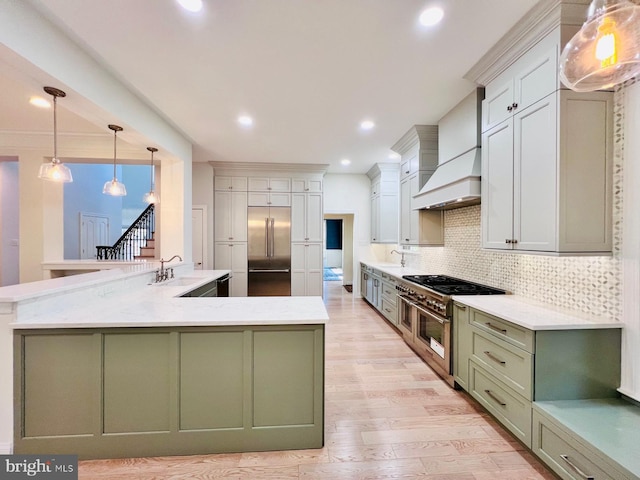 kitchen featuring sink, custom range hood, decorative backsplash, hanging light fixtures, and high quality appliances