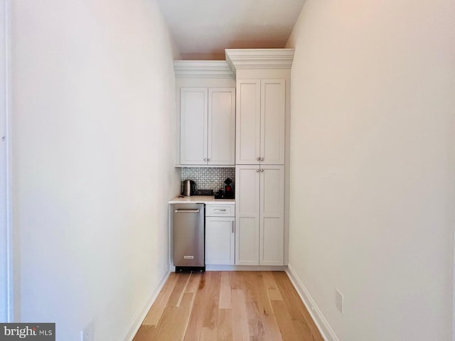 bar with light hardwood / wood-style flooring, white cabinetry, and tasteful backsplash