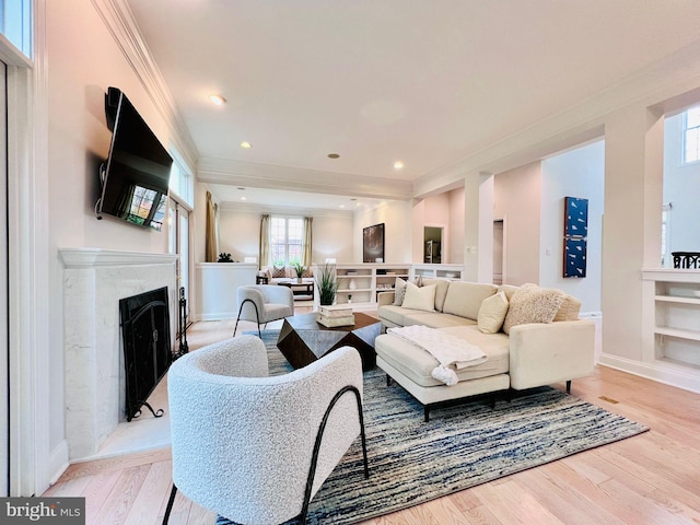 living room with a premium fireplace, light wood-type flooring, crown molding, and built in features