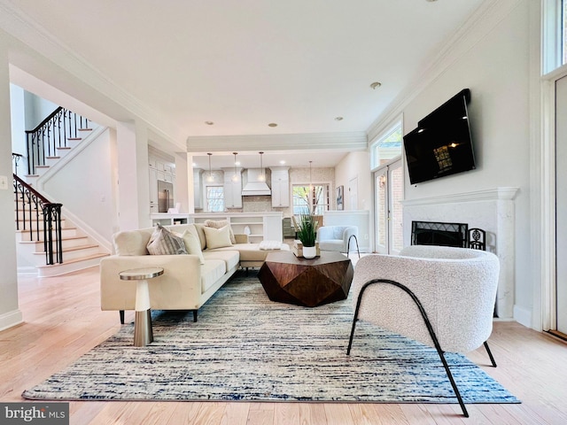 living room with a high end fireplace, light wood-type flooring, and ornamental molding