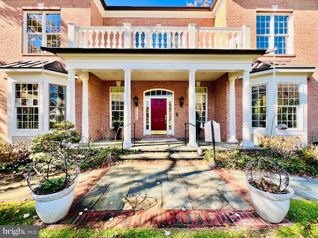 view of exterior entry with a balcony and covered porch