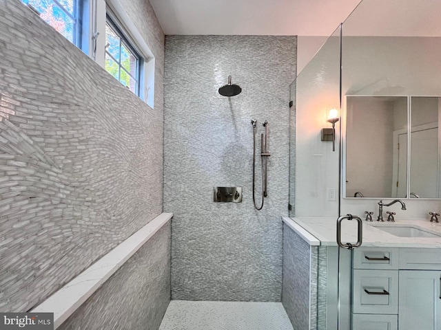 bathroom with tiled shower and vanity