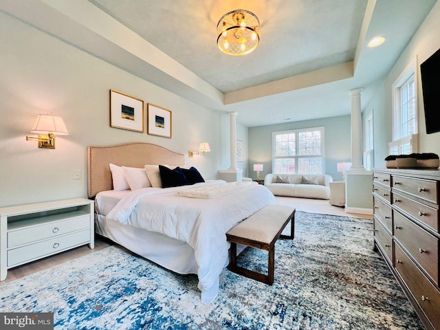 bedroom with ornate columns and a tray ceiling