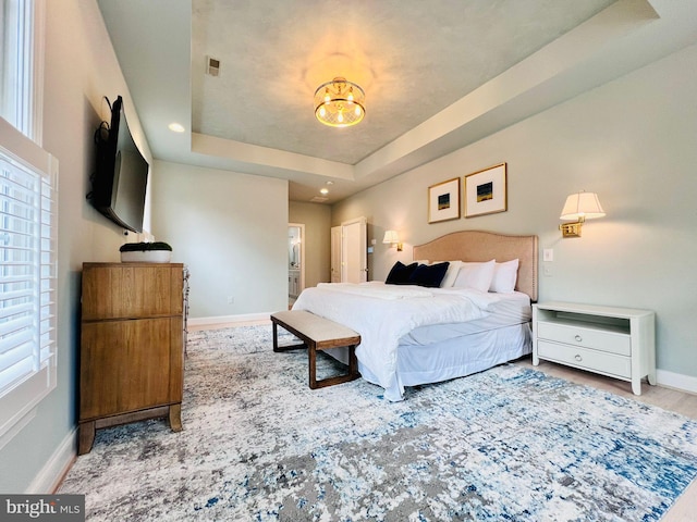 bedroom featuring light hardwood / wood-style floors and a raised ceiling