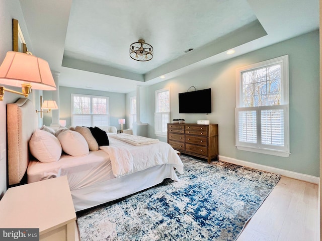 bedroom with wood-type flooring and a tray ceiling