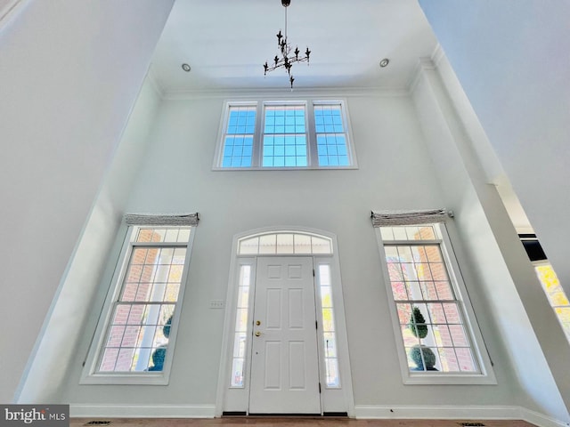 entryway featuring a towering ceiling and crown molding