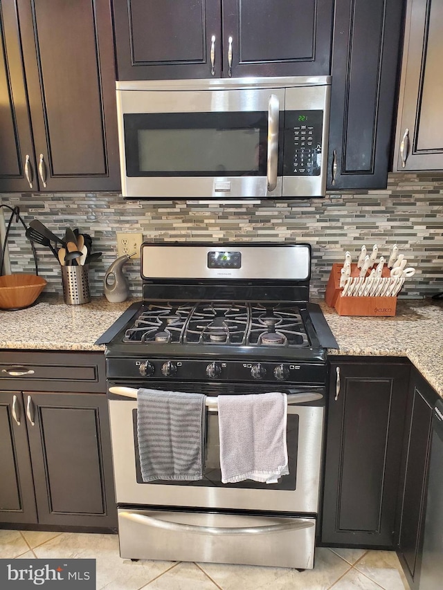 kitchen featuring decorative backsplash, light tile patterned floors, light stone countertops, and appliances with stainless steel finishes