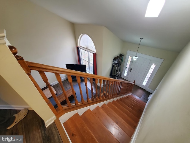 stairway featuring high vaulted ceiling and wood-type flooring