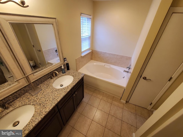 bathroom featuring tile patterned floors, a bathing tub, vanity, and toilet