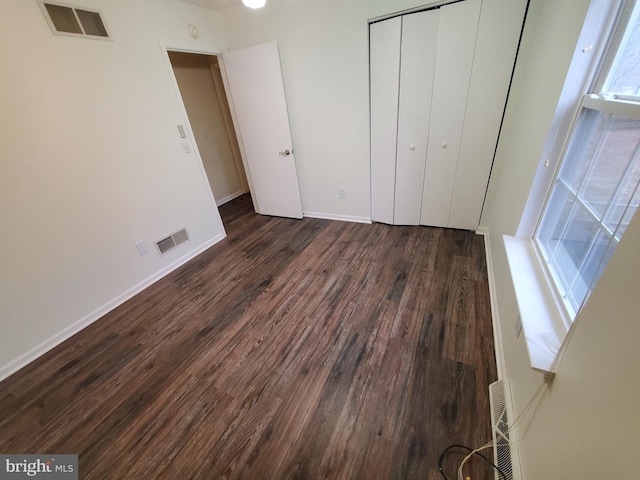 unfurnished bedroom with dark hardwood / wood-style flooring and a closet