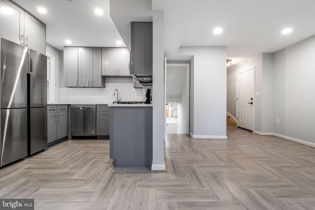 kitchen with gray cabinets, appliances with stainless steel finishes, decorative backsplash, and light parquet floors