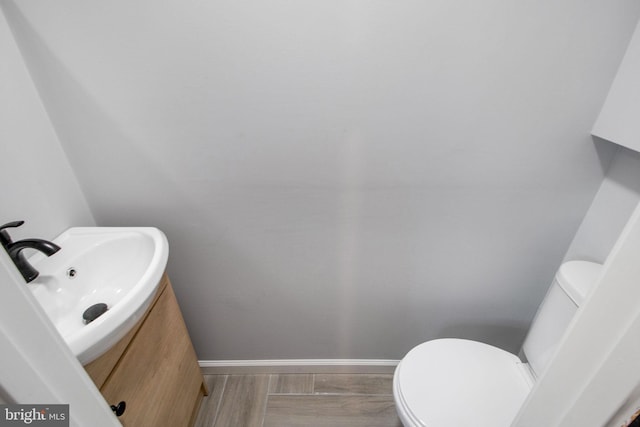 bathroom with toilet, sink, and wood-type flooring