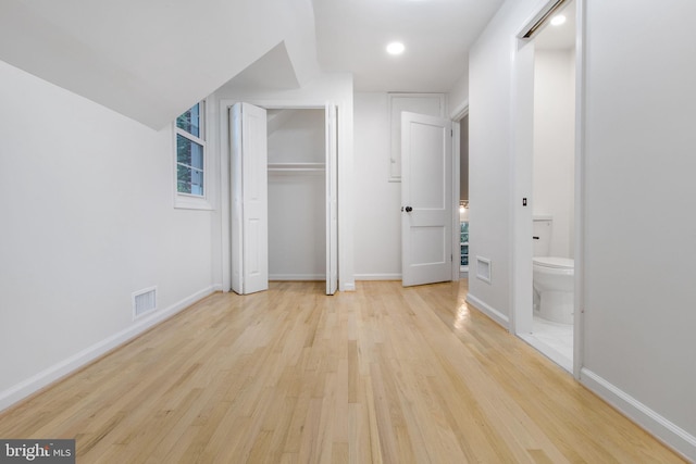 unfurnished bedroom featuring light hardwood / wood-style floors and ensuite bath