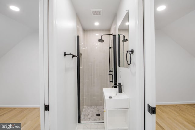 bathroom with hardwood / wood-style floors, sink, and tiled shower