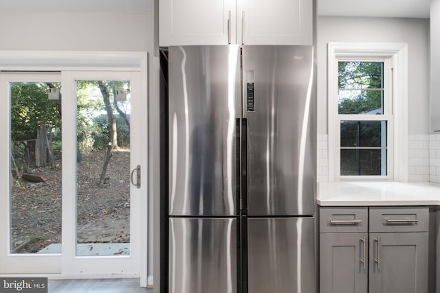 kitchen featuring gray cabinets, a wealth of natural light, tasteful backsplash, and stainless steel fridge