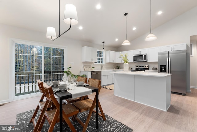 dining area with light wood finished floors, plenty of natural light, recessed lighting, and lofted ceiling