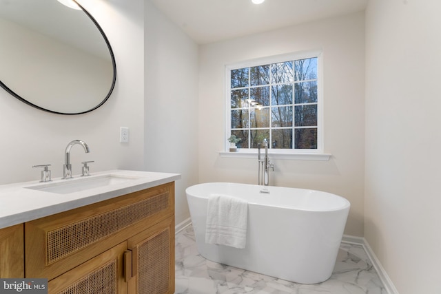 bathroom featuring baseboards, a freestanding bath, marble finish floor, and vanity