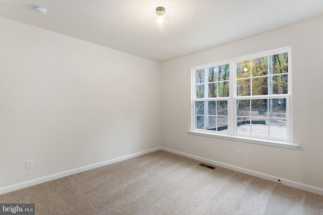 empty room with light colored carpet, baseboards, and visible vents