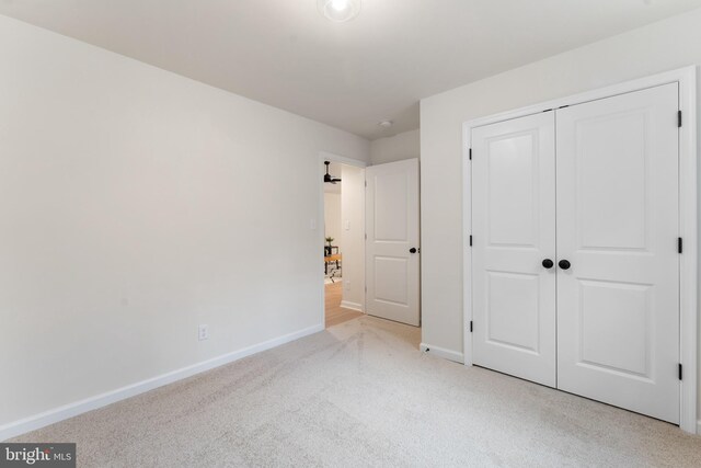 unfurnished bedroom with a closet, baseboards, and light carpet