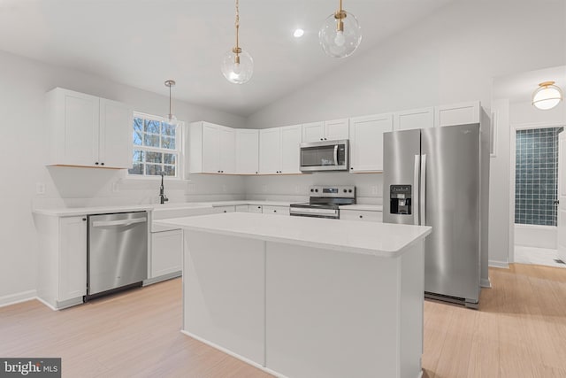 kitchen featuring lofted ceiling, white cabinets, hanging light fixtures, appliances with stainless steel finishes, and a kitchen island