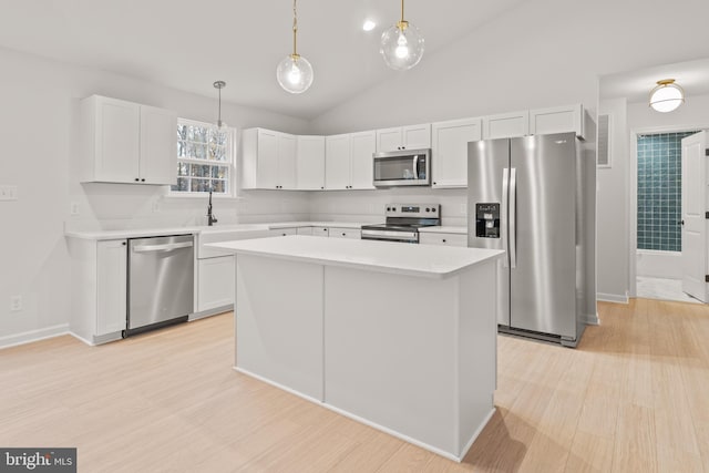 kitchen with hanging light fixtures, white cabinets, appliances with stainless steel finishes, a kitchen island, and light wood-type flooring