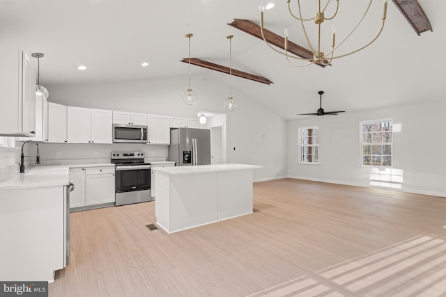 kitchen featuring appliances with stainless steel finishes, beam ceiling, decorative light fixtures, light hardwood / wood-style flooring, and white cabinetry