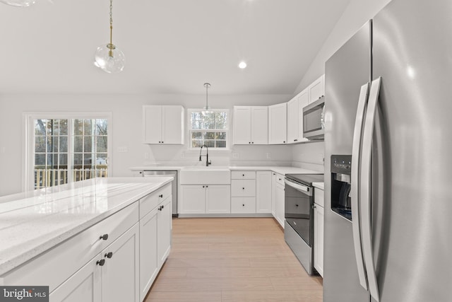 kitchen featuring white cabinets, hanging light fixtures, appliances with stainless steel finishes, and vaulted ceiling